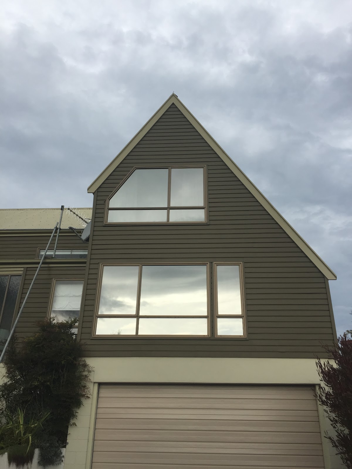 Two storey home exterior repainted in olive and cream