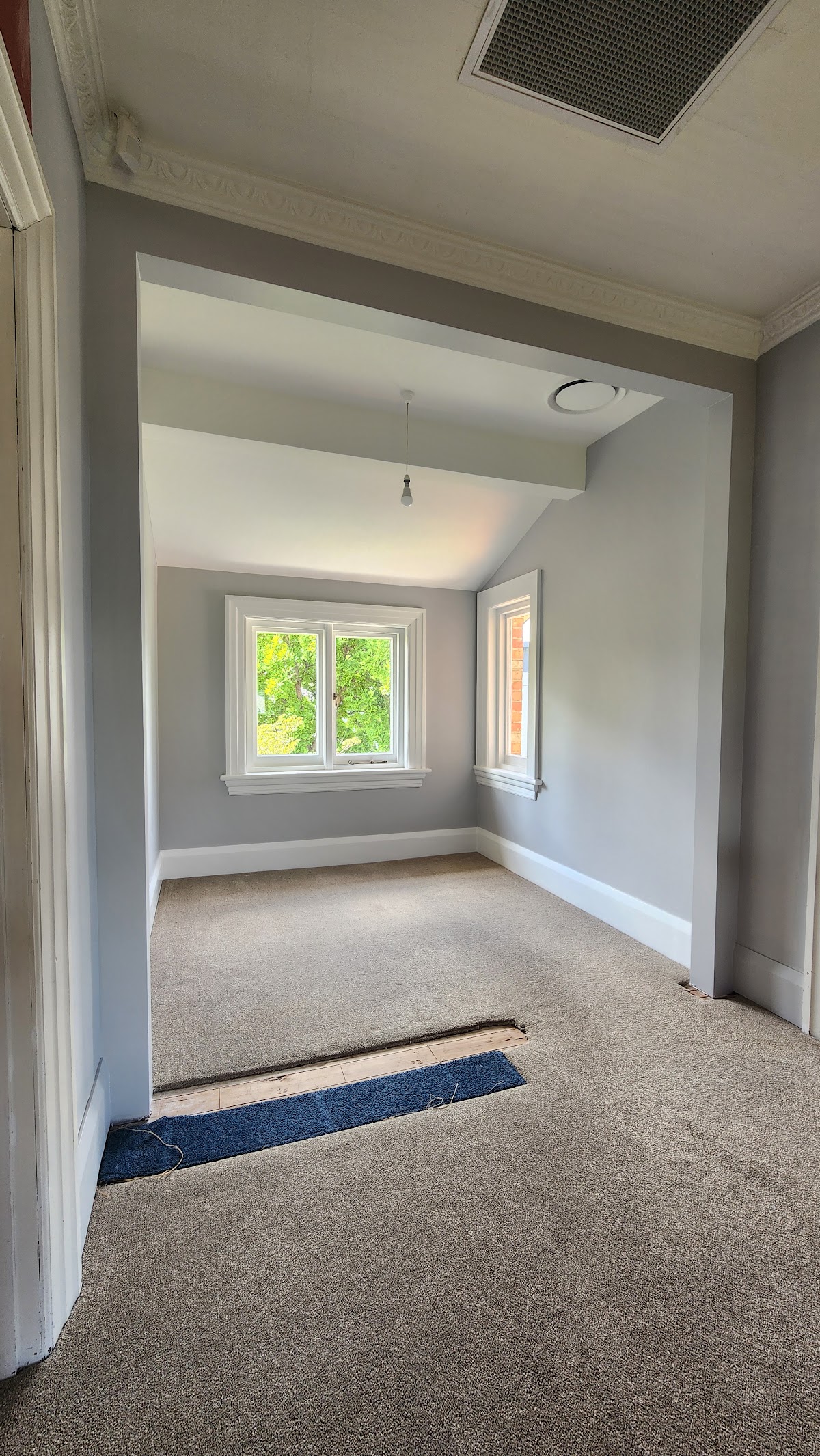 Freshly painted interior room with soft grey walls, white trim and ornate cornice work